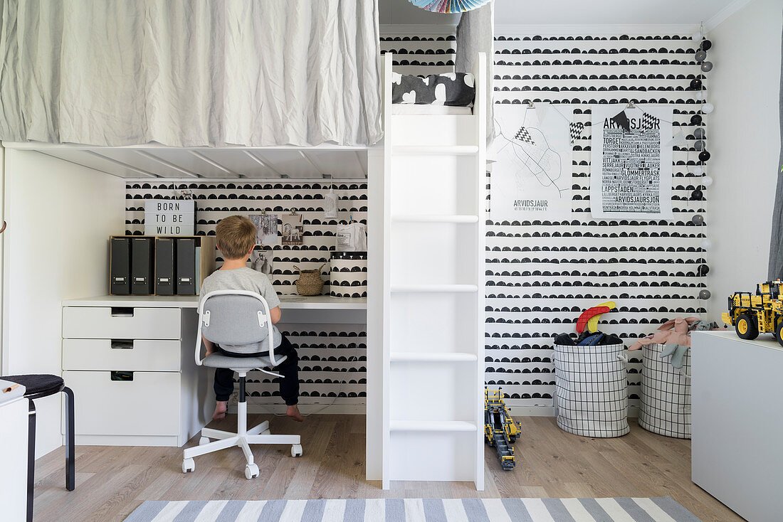 Hochbett mit Schreibtisch im Kinderzimmer mit schwarz-weißer Wand, Junge am Schreibtisch