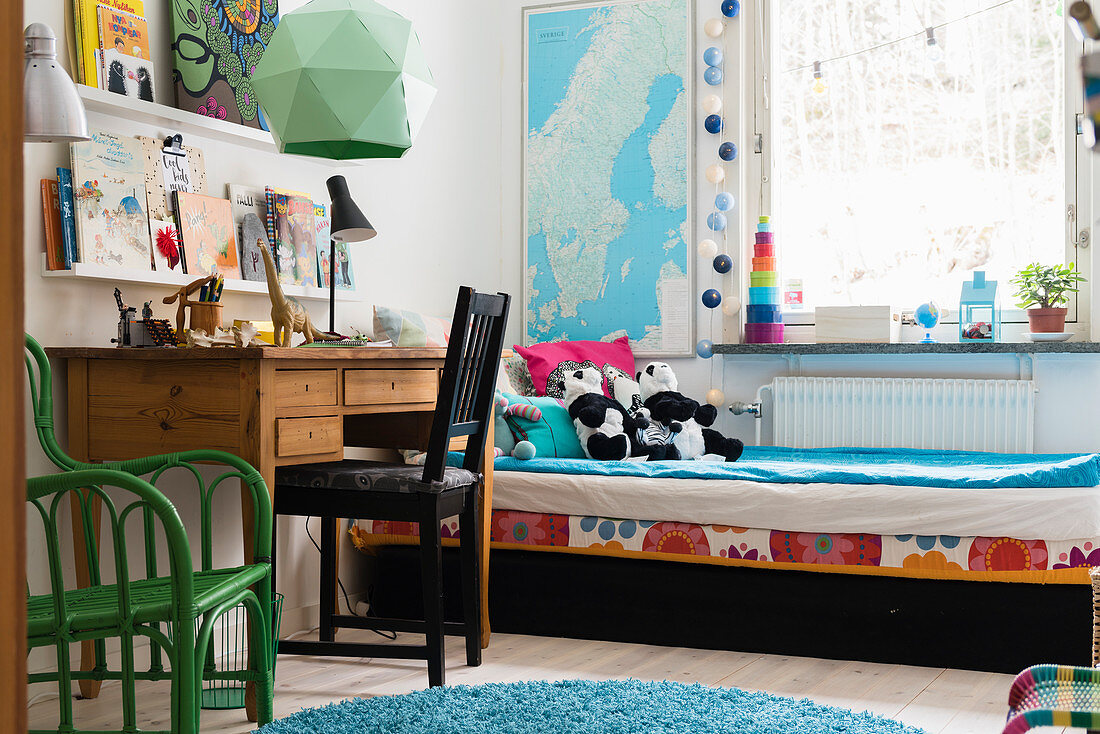 Soft toys on bed, wooden desk and chair in child's bedroom