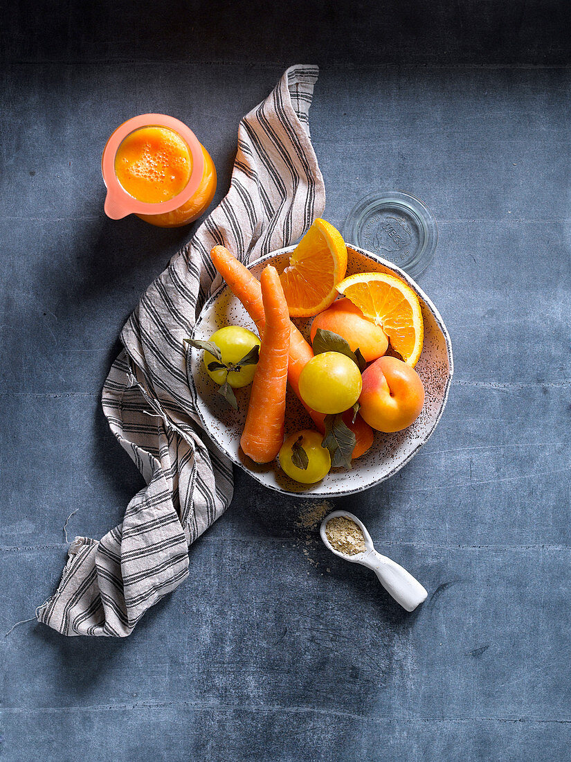 Orange and yellow fruit and vegetable on bowl on shabby blue table