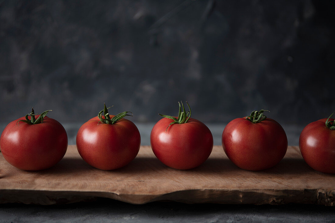 Tomaten, aufgereiht, auf Holzbrett