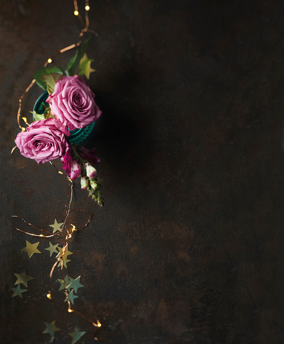 Festive arrangement of pink roses, fairy lights and gold stars