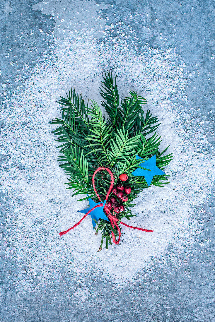 Kiefernzweige mit roten Beeren und blauen Sternen als Weihnachtsdekoration