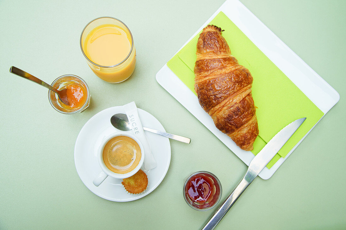 Französisches Frühstück; Kaffee, Croissant, Orangensaft und Marmelade