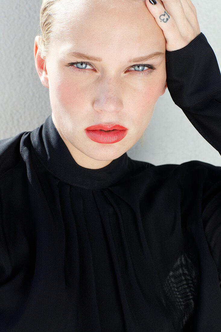 A young blonde woman with red lipstick and a black blouse