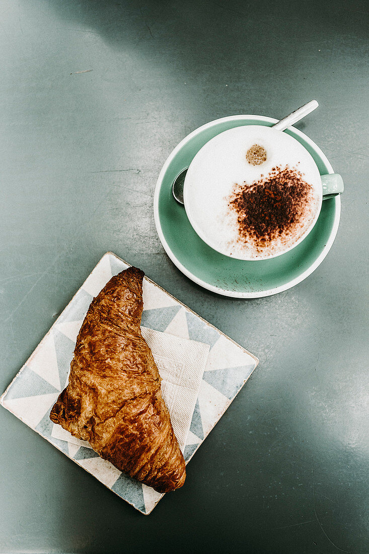 Ein Croissant und eine Tasse Cappuccino