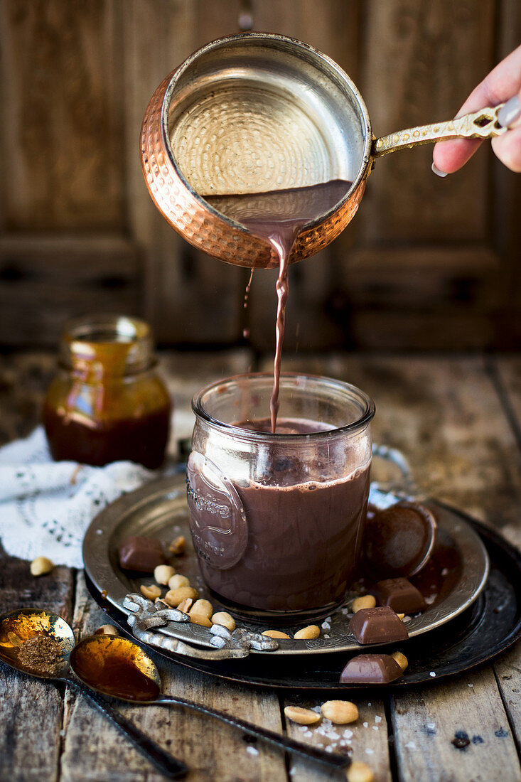 Hot chocolate with peanut caramel being poured into a cup