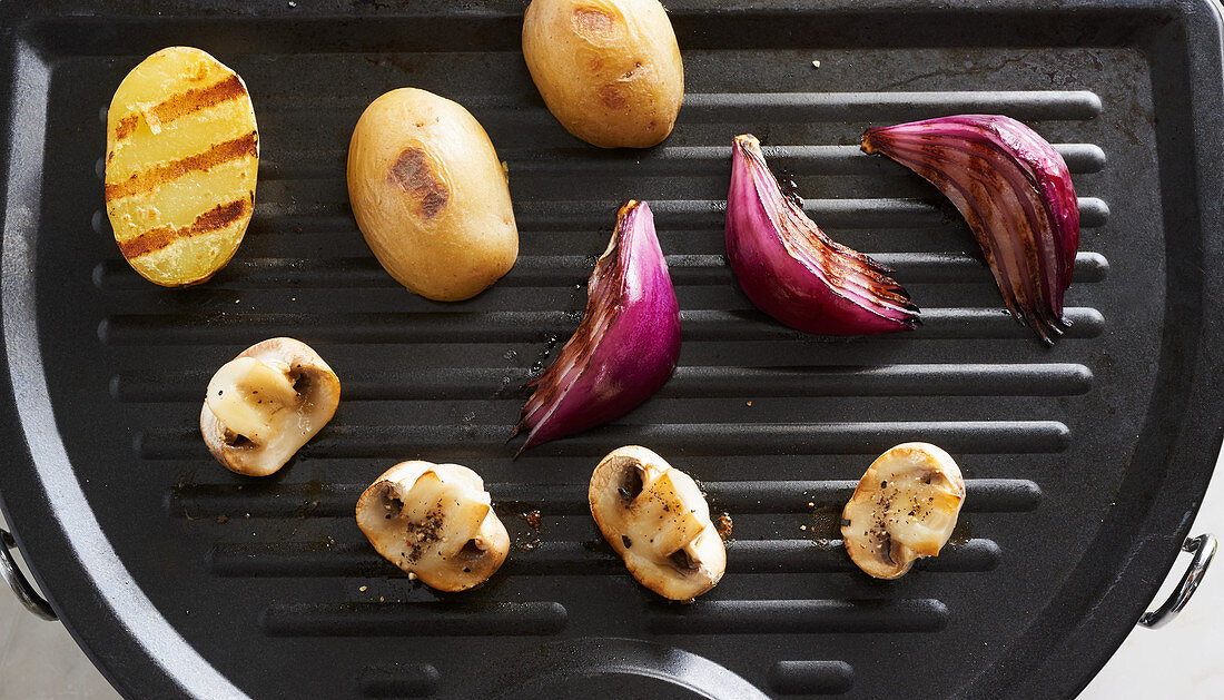 Kartoffeln, rote Zwiebeln und Champignons auf der Grillplatte