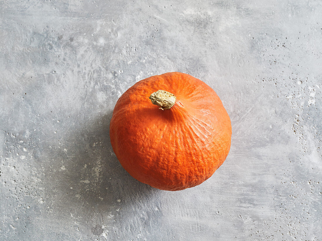 A Hokkaido pumpkin on a grey stone surface