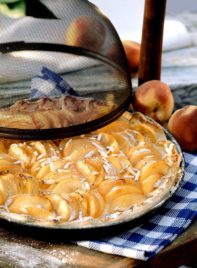 Peach tart in round baking dish, decoration: food cover