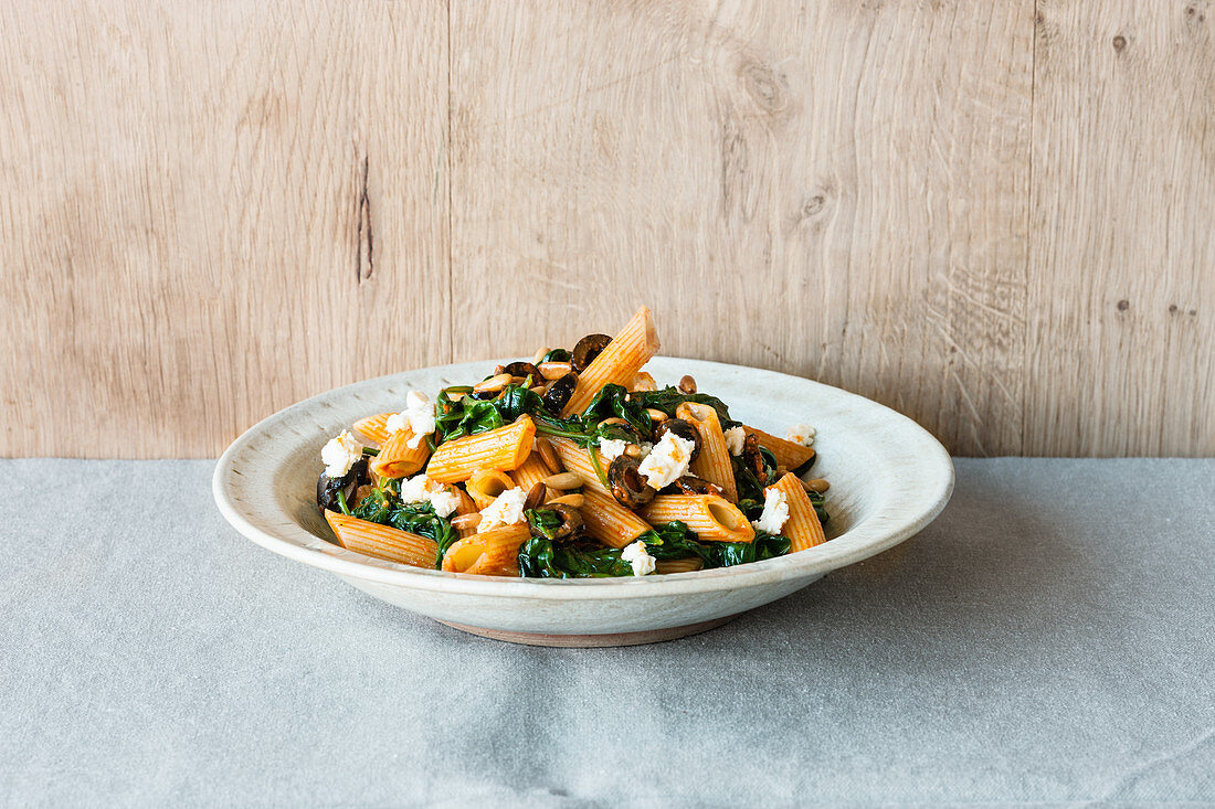 Penne pasta with harissa and spinach sauce, feta cheese and black olives