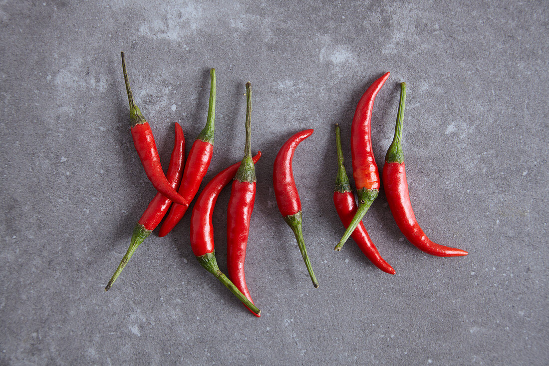 Red chilli peppers on a grey surface (seen from above)