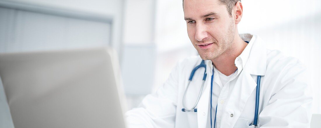 Male doctor using laptop and concentrating