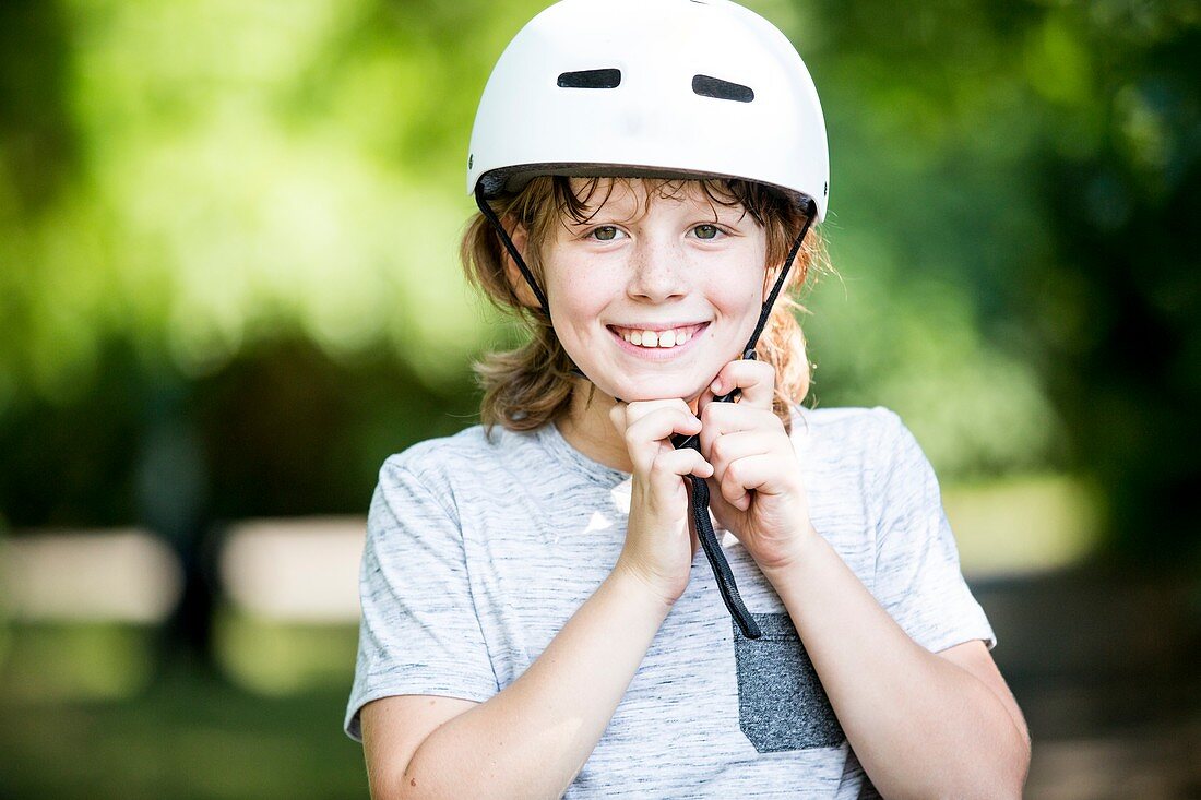 Boy fastening bicycle helmet