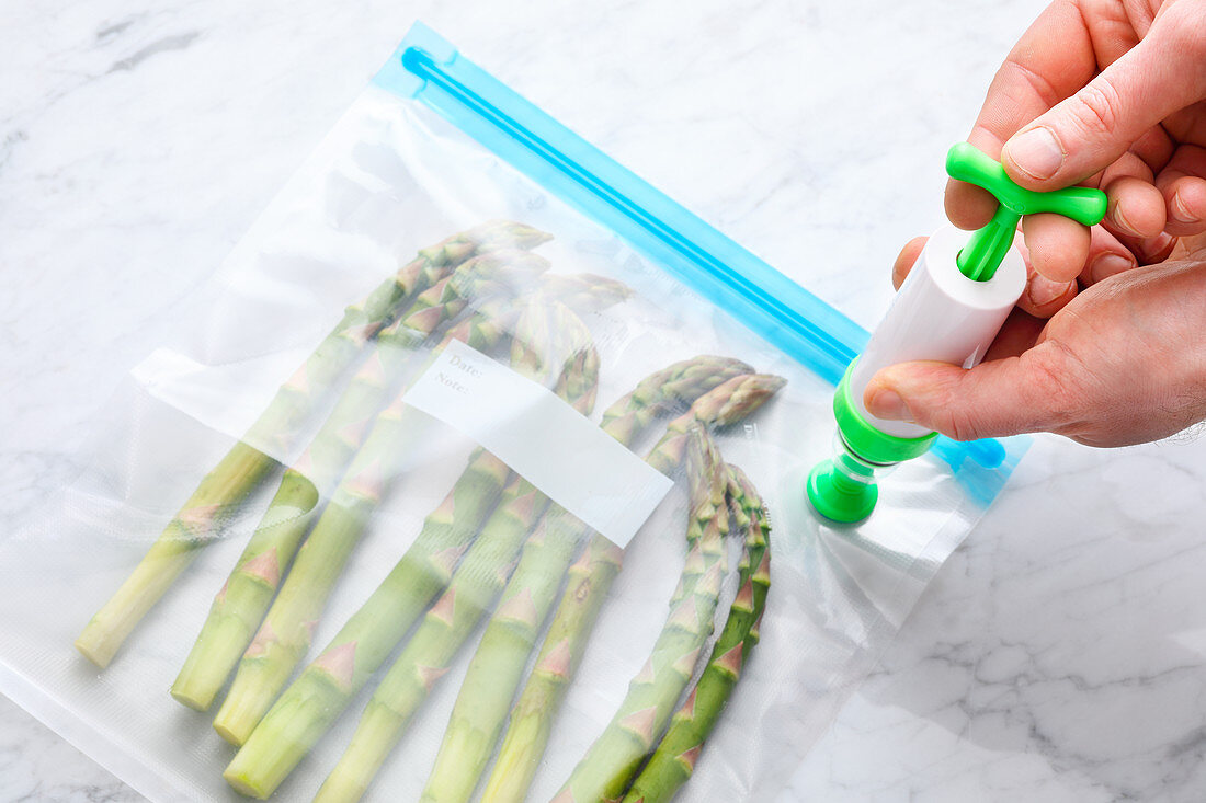 Green asparagus being vacuum packed with a hand pump