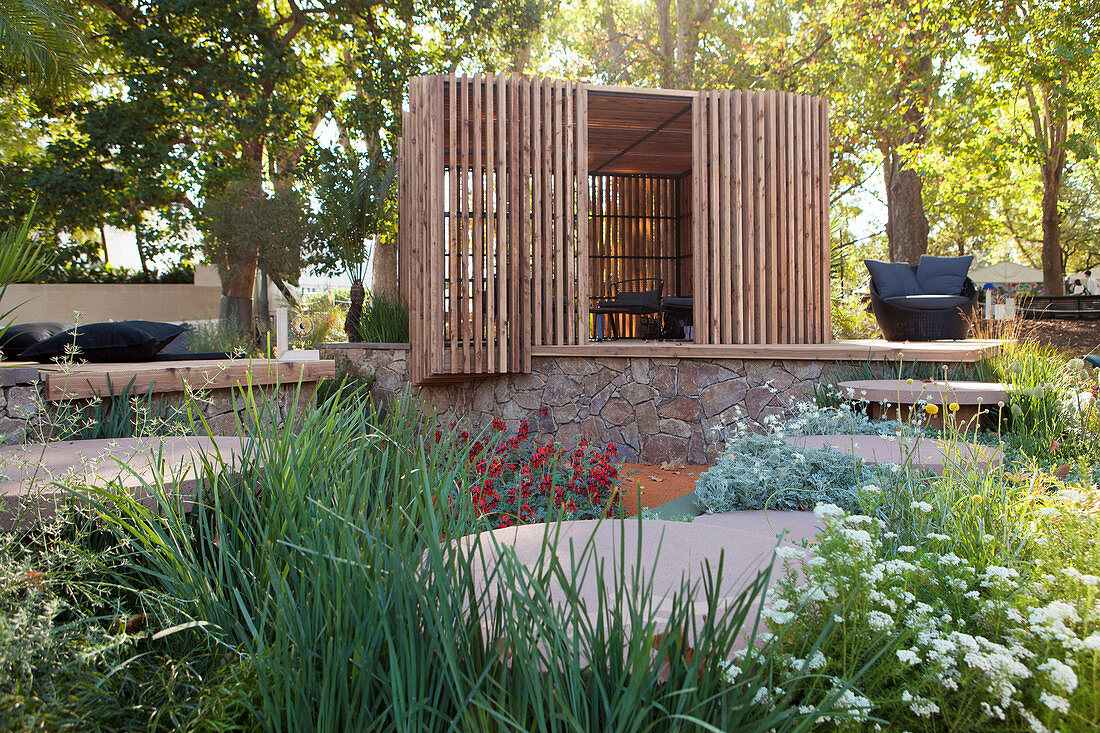 Holzpavillon auf halbhoher Natursteinmauer im Garten