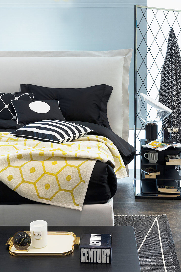 Schwarz-weiße Bettwäsche und gelbe Decke auf weißem Doppelbett mit Bettkopfteil