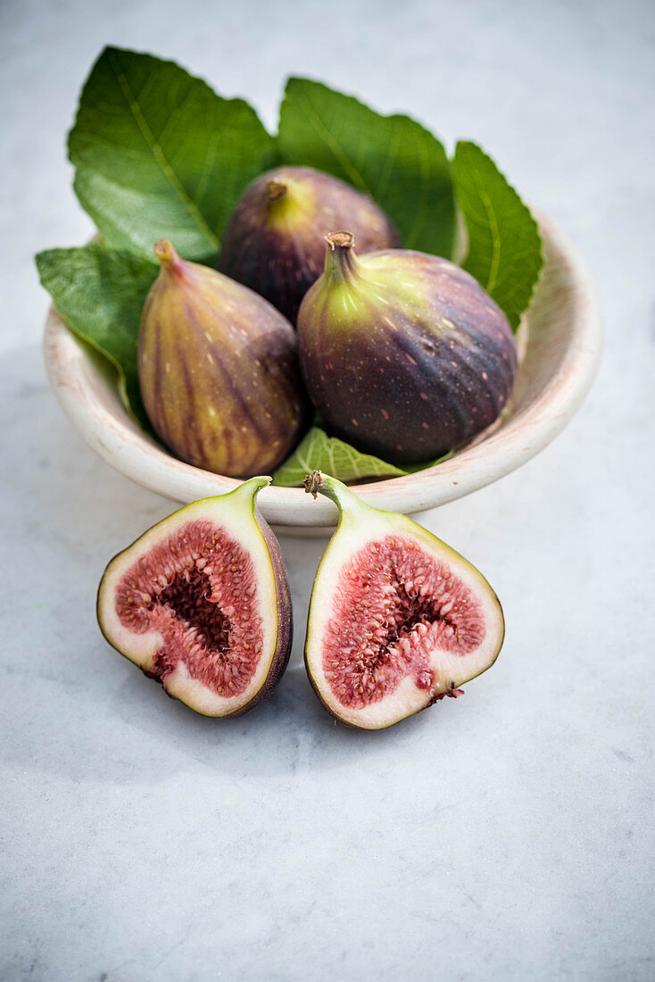 Fresh purple figs in a bowl, one halved