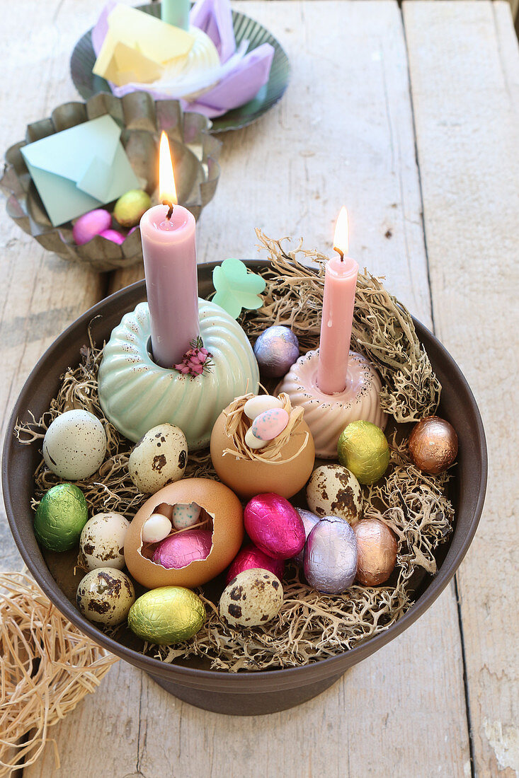 An arrangement of various Easter eggs, quail's eggs and burning candles