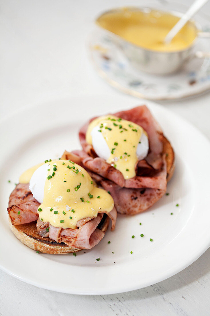 Poached eggs with hollandaise sauce on top of bacon and a muffin