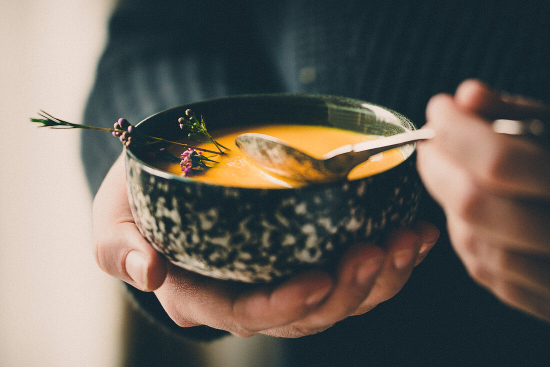 A woman holding a cup of pumpkin soup