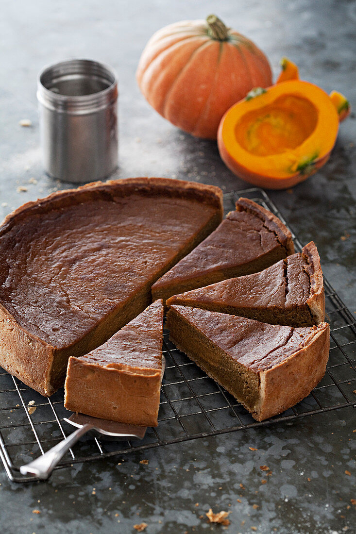 Sliced pumpkin tart with pumpkins in background