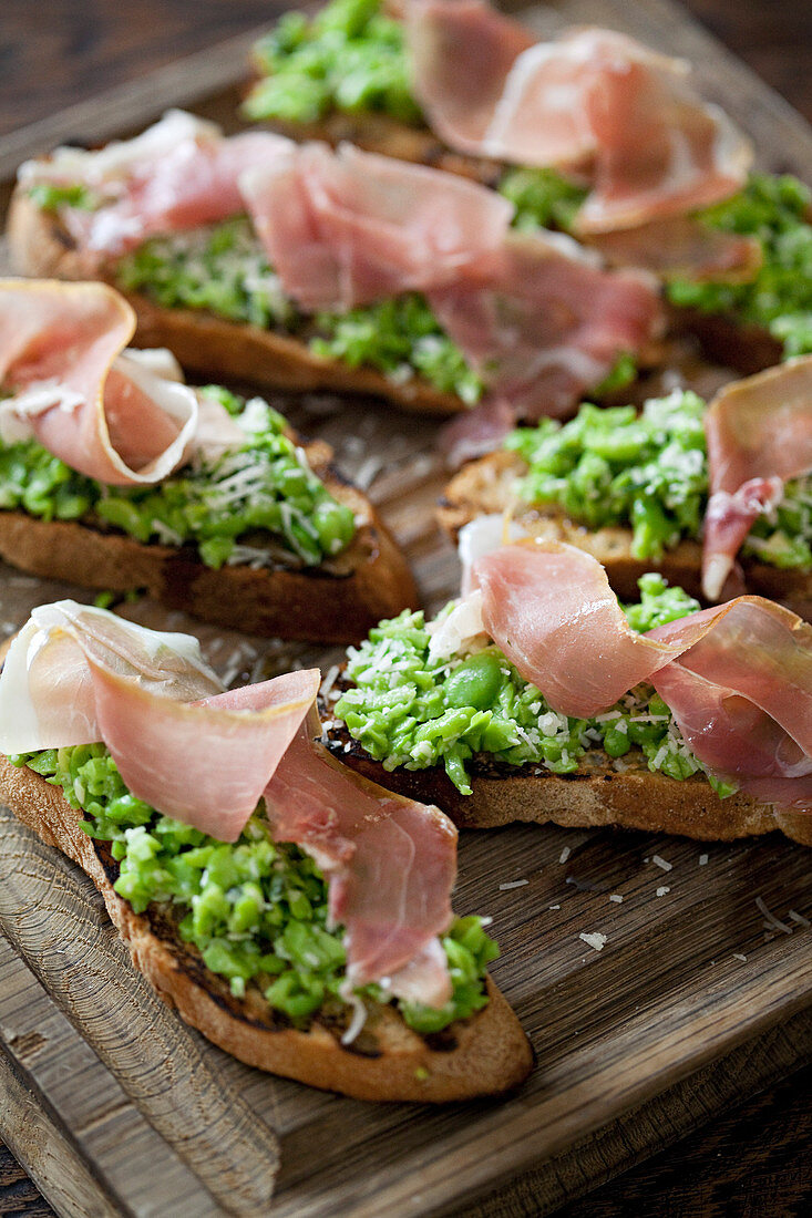 Mashed broad beans on toast topped with parma ham and parmesan