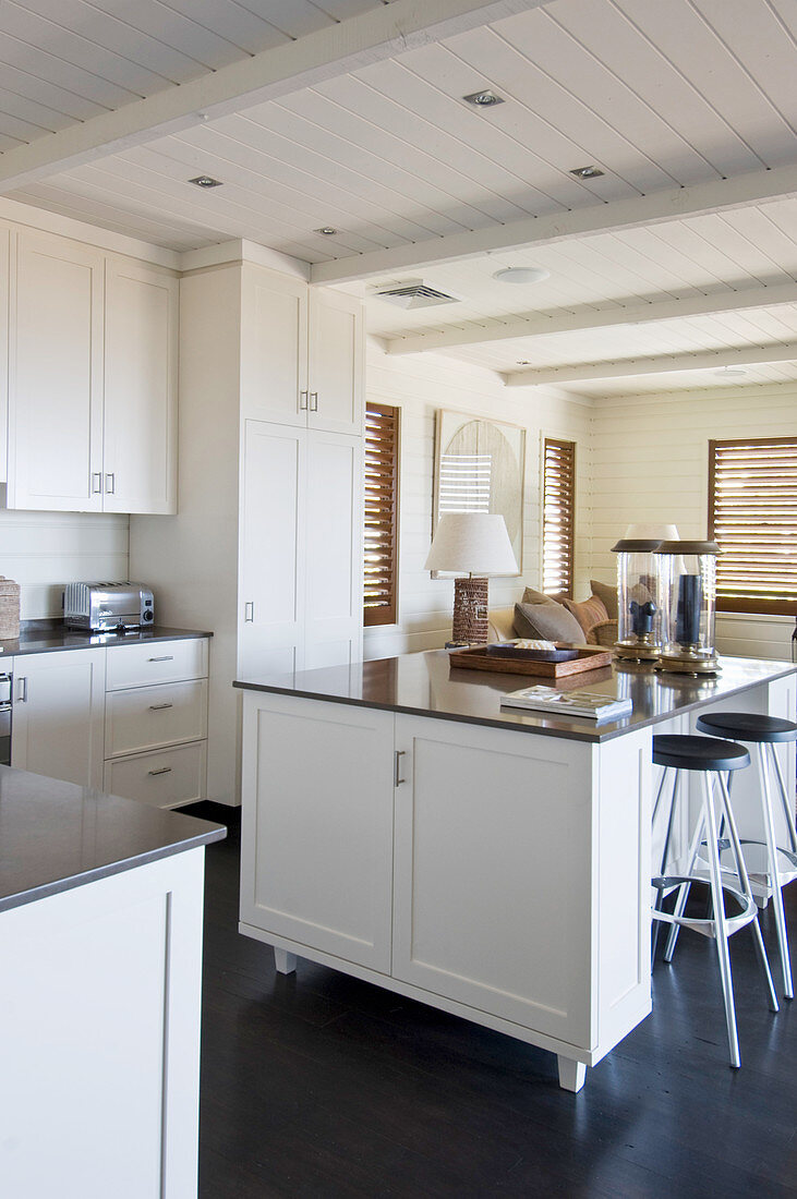 Island counter in open-plan kitchen with white panelled cabinets