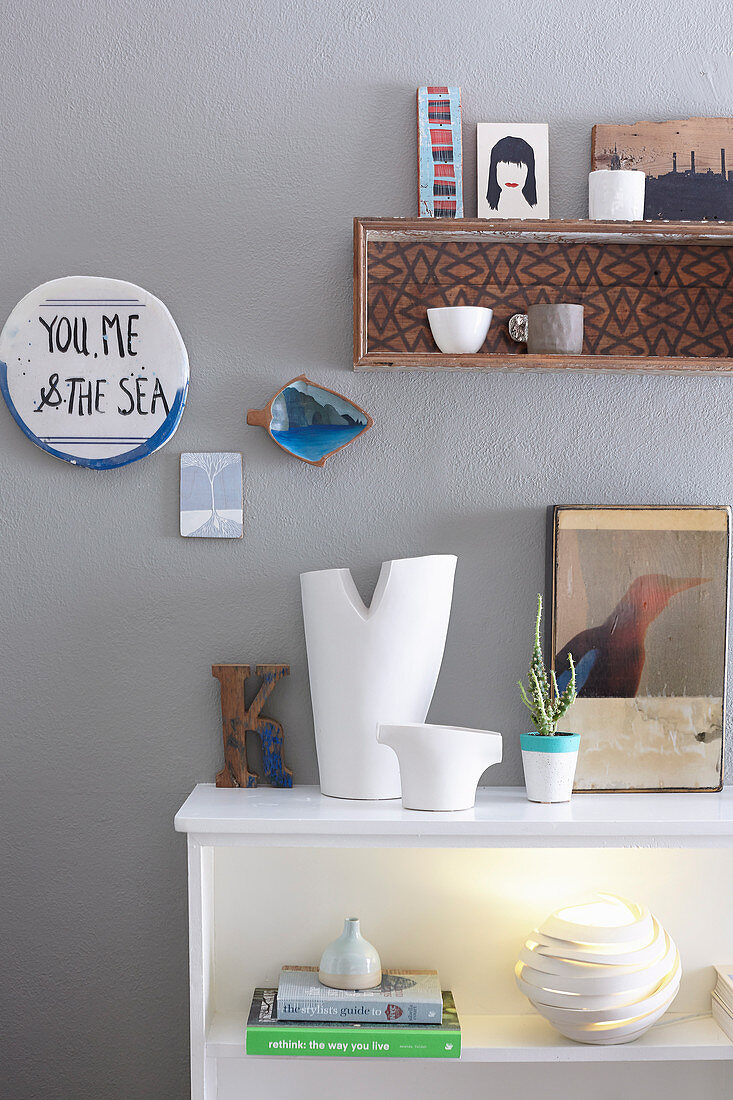 Sideboard with vases, picture and table lamp, above message and hanging shelf with decorative objects