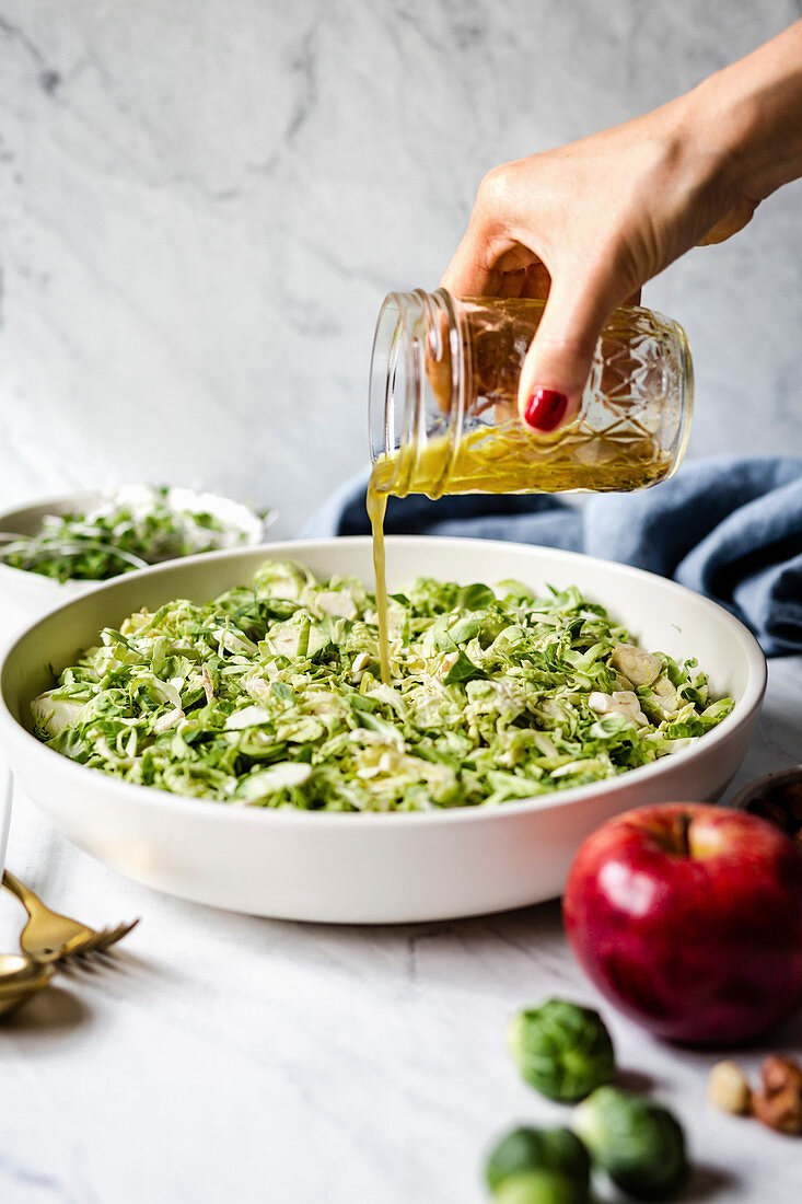 Rosenkohlsalat wird mit Dressing beträufelt