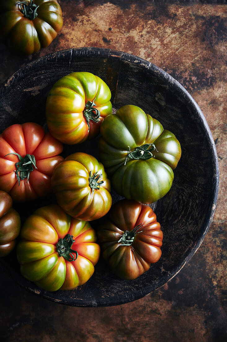 Frisch geerntete Heirloom Tomaten in schwarzer Schale (Aufsicht)