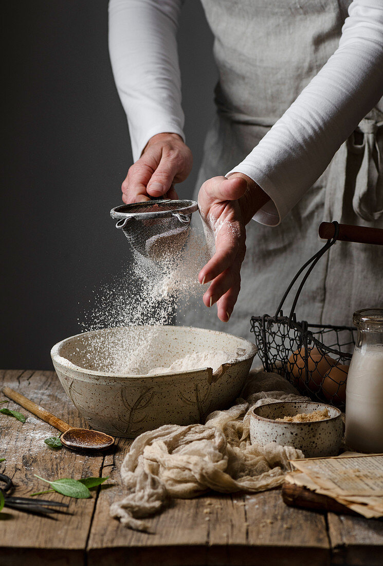 A woman sifting flour into a bowl to make pumpkin scones