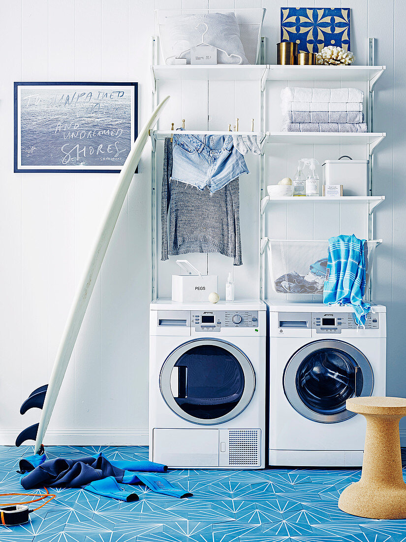 Washer and dryer, white shelves above in the washroom with light blue cement tiles