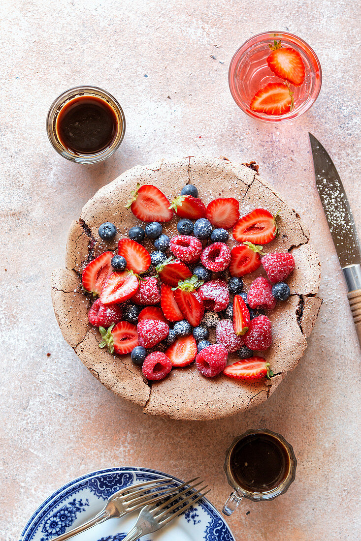 Chocolate meringue cake topped with fresh fruit on the table
