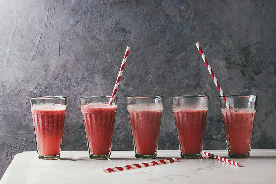 Red fruit berries watermelon iced cocktail in glasses in row with striped straw