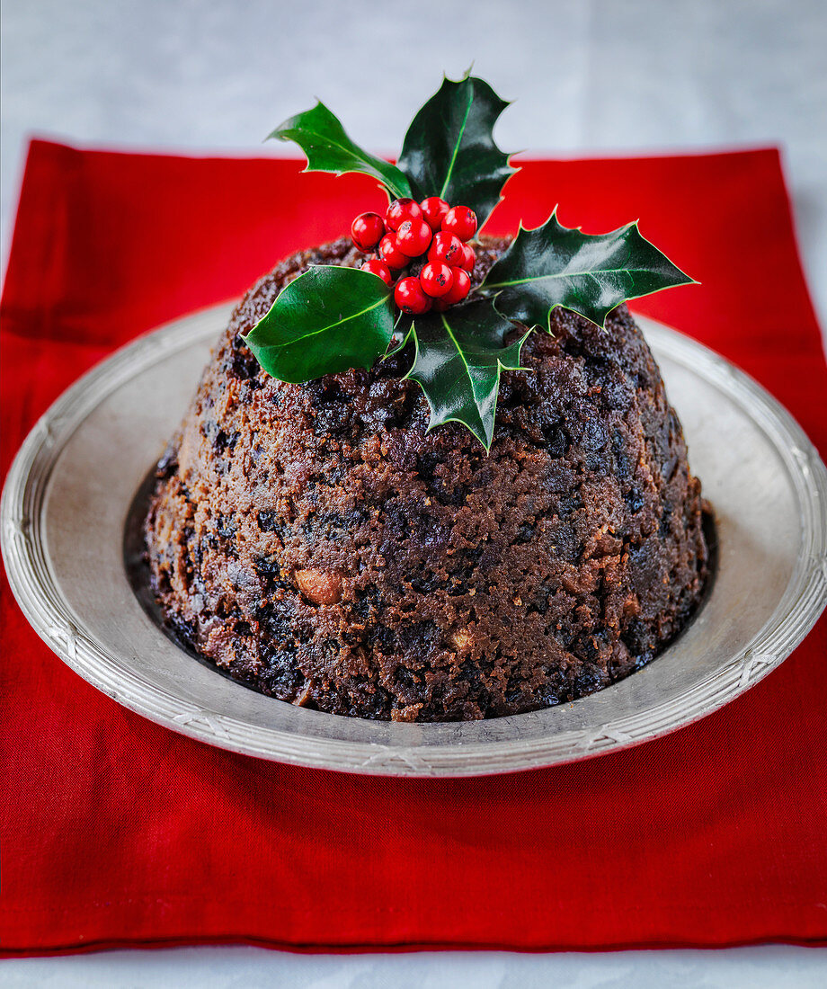 Englischer Christmas Pudding dekoriert mit Stechpalmenzweig