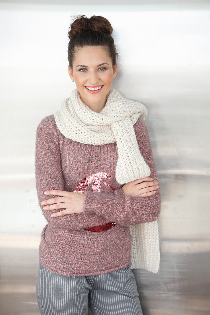 A brunette woman wearing a white scarf with a mottled pink-grey knitted jumper