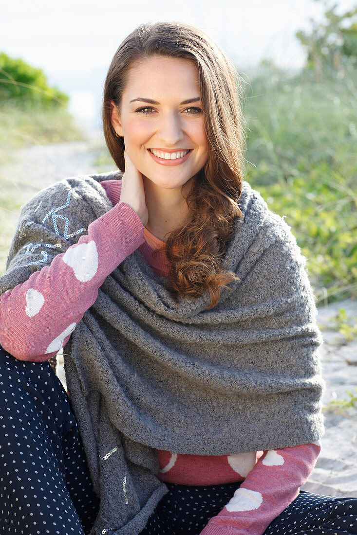 Brünette Frau mit grauem Schultertuch im rosa Strickpullover mit Herzen