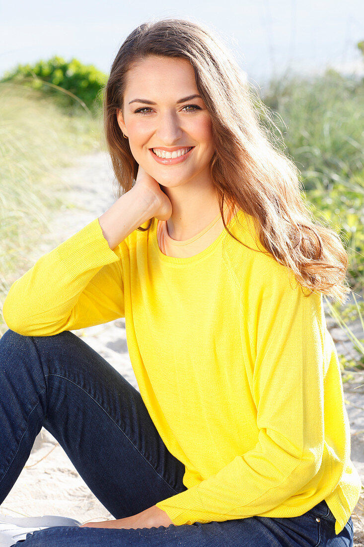 Brünette Frau in gelbem Pullover und Jeans