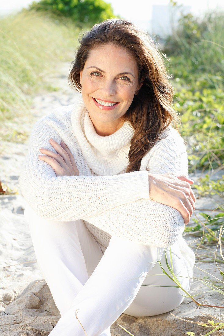 Brunette woman wearing white knit sweater and white trousers