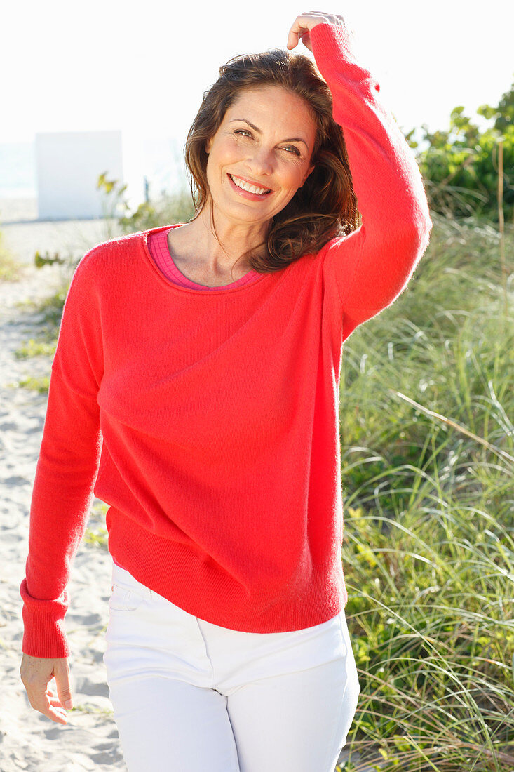 Brunette woman wearing red knit sweater and white trousers