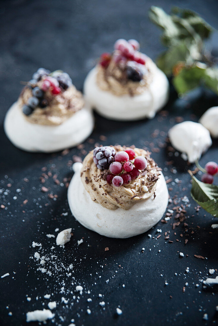 Vegan pavlova made with aquafaba, topped with coffee butter cream and frozen berries