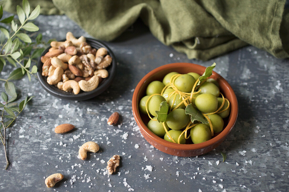 A bowl of green olives wth mixed nuts