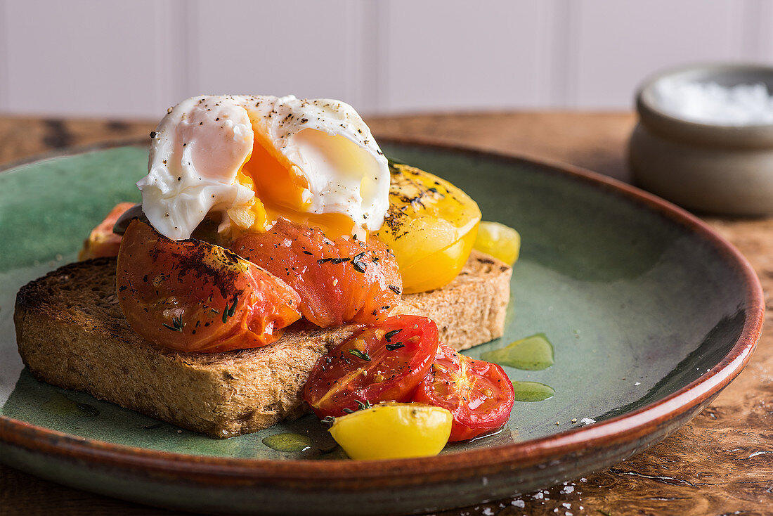 A slice of bread topped with roasted tomatoes and a poached egg