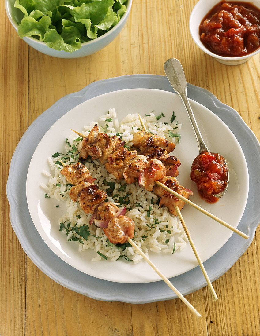 Chicken skewers on parsley rice with tomato salsa