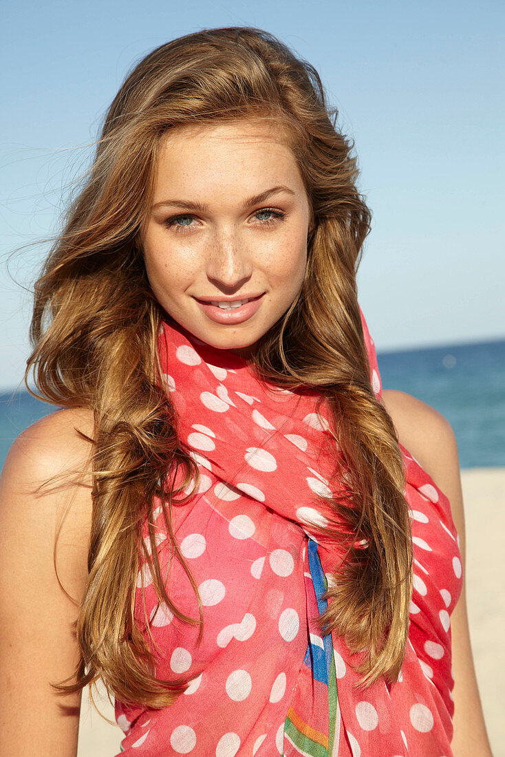 A young blonde woman by the sea wearing a beach towel