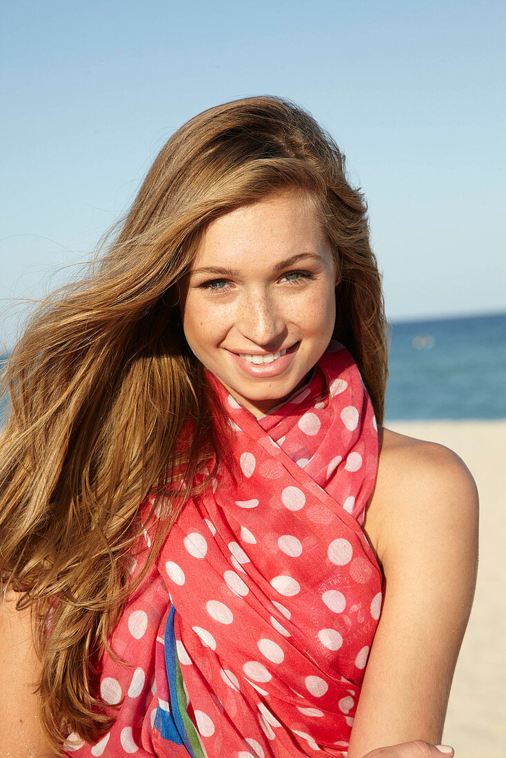 A young blonde woman by the sea wearing a beach towel