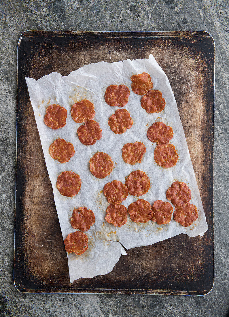 Homemade salami chips on a baking tray