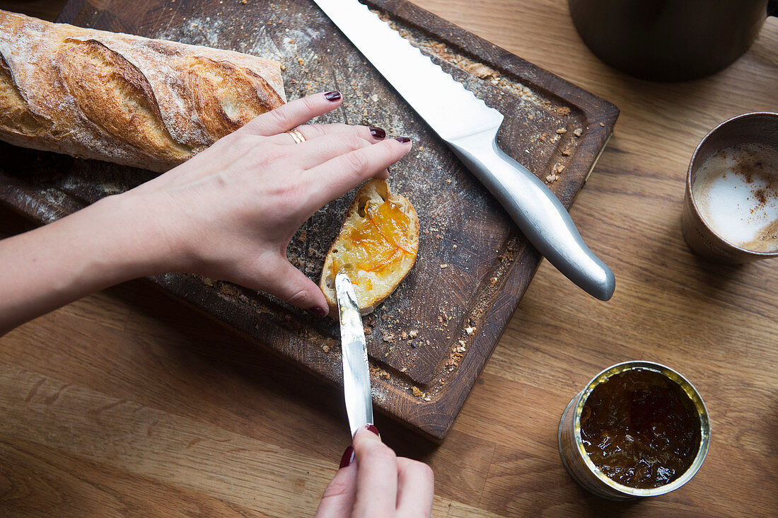 A woman spreading marmalade on a slice of bread