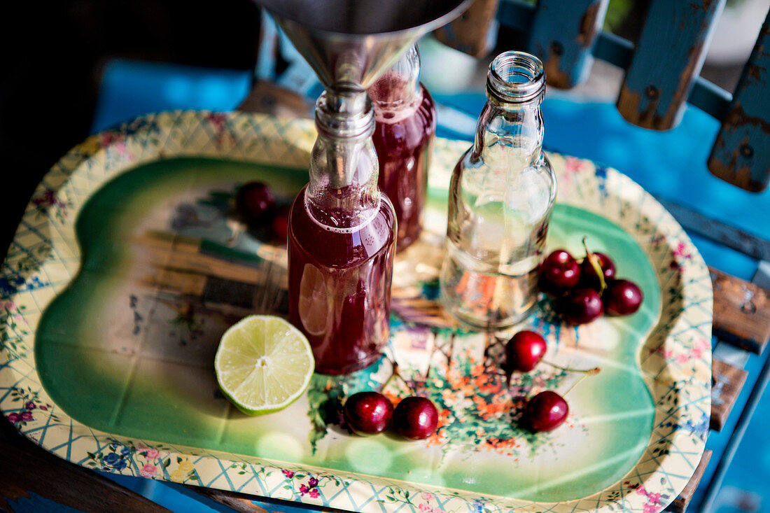 Kirschsaft mit Limette und Orange in Flaschen abfüllen