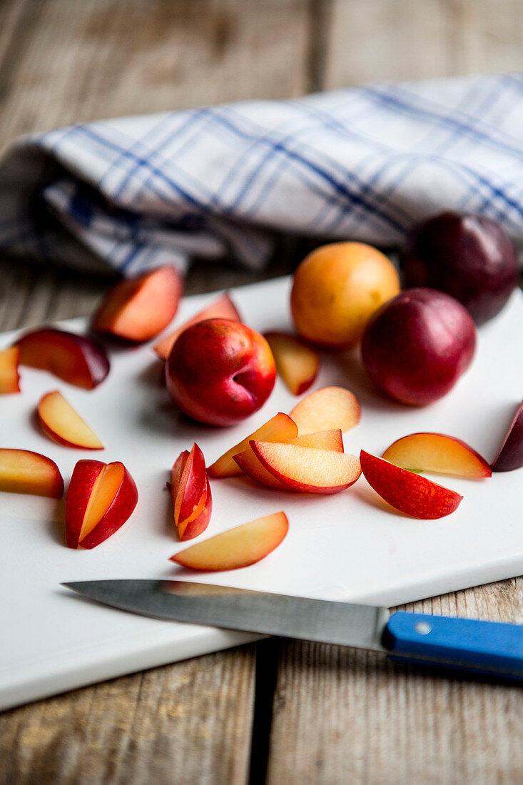 Plums, whole and sliced, on a chopping board